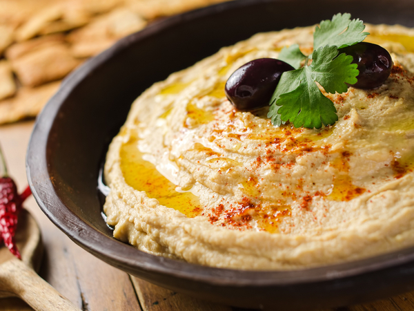 Ein Schälchen gefüllt mit frischem Humus, dekoriert mit Oliven und Petersilie Ein Schälchen gefüllt mit frischem Humus, dekoriert mit Oliven und Petersilie